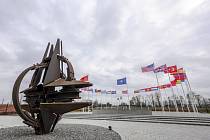 Vlajky členských zemí NATO a znak organizace před sídlem v Bruselu. Ilustrační snímek