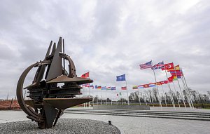 Vlajky členských zemí NATO a znak organizace před sídlem v Bruselu. Ilustrační snímek