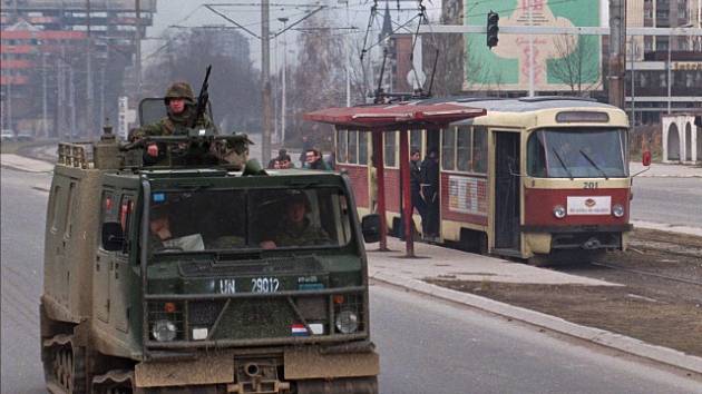 Obrněný transportér projíždí Sarajevem, v pozadí tramvaj na zastávce. Snímek z 1. prosince 1995