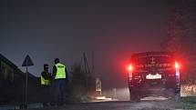 Vůz pohřební služby zaparkovaný vedle dvou policistů, kteří zajišťují přístup na místo výbuchu ve vesnici Przewodów.