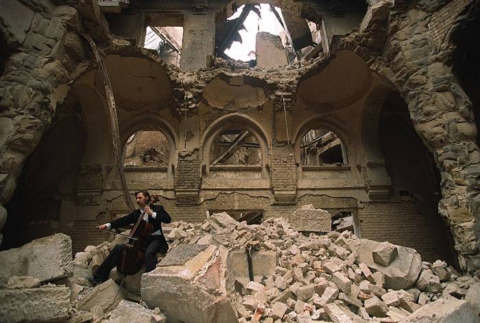 Sarajevo, obležení v roce 1992. Do polozbořené budovy Národní knihovny přišel zahrát na violoncello místní sarajevský muzikant Vedran Smailović, jenž během obléhání hrál často zdarma na různých pohřbech, byť se stávaly terčem srbských sil