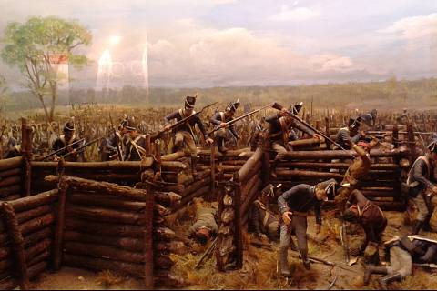Bitva v ohybu podkovy, březen 1814. Vojáci generála Andrewa Jacksona útočí na opevnění Rudých holí, což byli vzbouření indiáni kmene Kríků