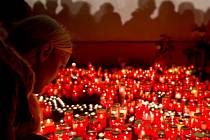 Lidé zapalují svíčky před klubem Colectiv, kde při požáru zemřely desítky lidí.