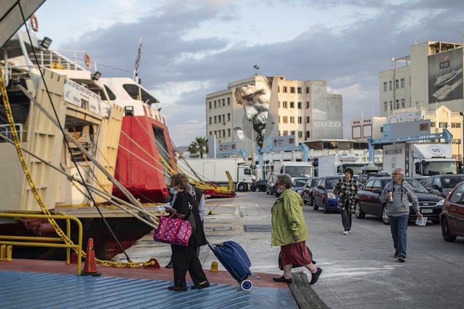 Lidé v rouškách nastupují na palubu trajektu v řeckém přístavu Pireus