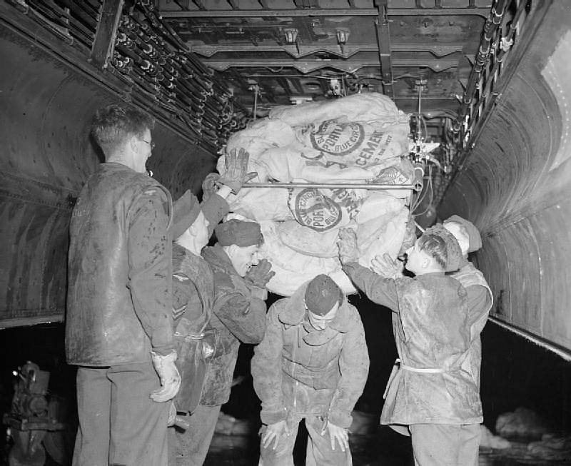 Vojáci nakládají zásoby jídla do bombardovacího letadla Lancaster britské RAF