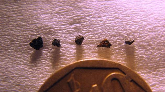 Drobné kousky kamene Hypatia, nalezeného v Egyptě, na základě jejichž analýzy vědci usuzují, že kámen je pozůstatkem exploze supernovy. Velikost fragmentů ilustruje k nim přiložená mince.