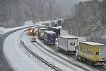 Husté sněžení a silný vítr od rána 4. prosince 2021 komplikuje provoz v Ústeckém kraji. Na snímku sypač projíždí podél kolony kamionů u výjezdu 74 na dálnici D8.