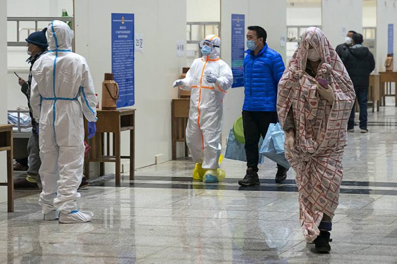 Zdravotníci v ochranných oblecích pomáhají pacientům nakaženým koronavirem v nemocnici ve Wu-chanu
