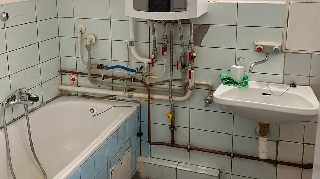 Původní koupelna je plná přiznaných vodovodních, plynových i odpadních trubek.