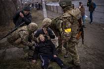 Ukrajinští vojáci pomáhají bezvládné ženě při evakuaci obyvatel z města Irpiň u Kyjeva