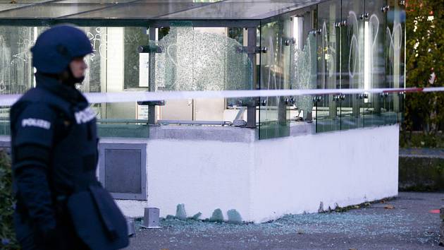 Rakouský policista hlídkuje 3. listopadu 2020 ve Vídni den po střeleckém útoku, v pozadí vjezd do garáží s rozbitými skly.