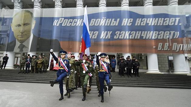 Výročí anexe Krymu. Na snímku mladí s nápisem „Rusko války nezačíná, ale ukončuje“ v Jaltě 17. března 2023