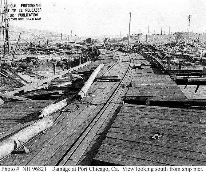Situace po explozi. Snímek zachycuje v pravé části zničenou budovu přístavní truhlárny, vlevo od středového stožáru jsou zbytky zkroucené oceli