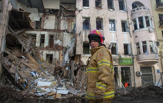 Hasič před zničenou obytnou budovou v ukrajinském Charkově.
