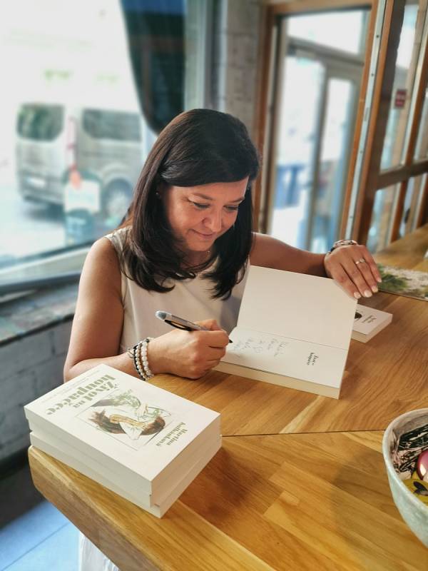 Martina Kulhánková podepisuje knihu při křtu v Činoherní kavárně v Praze.