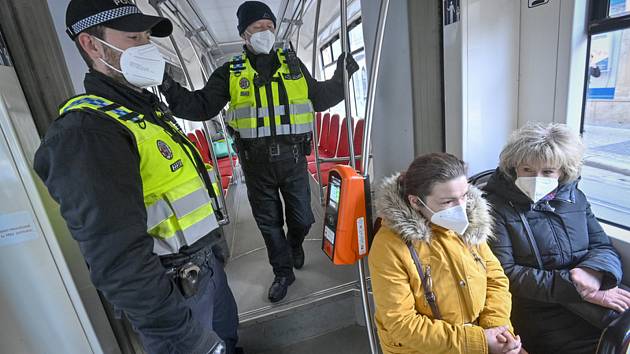Příslušníci městské policie dohlížejí 25. února 2021 v tramvaji pražské MHD na dodržování nově zavedené povinnosti nosit na frekventovaných místech respirátor nebo dvě jednorázové zdravotnické roušky přes sebe.