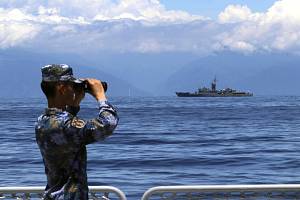 Čínský voják sleduje dalekohledem tchajwanskou fregatu během cvičení ve vodách kolem Tchaj-wanu, 5. srpna 2022