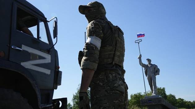 Ruský voják v Mariupolu u vojenského auta se symbolem Z.