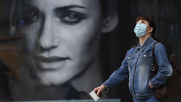 Žena v ochranné roušce proti koronaviru u obchodního centra.