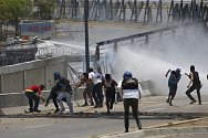 Protivládní demonstranti během střetů s bezpečnostními složkami u vojenské základny na okraji Caracasu (1. května 2019).