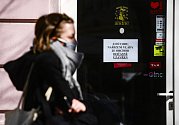 Žena s rouškou na obličeji 24. března 2020 prochází kolem zavřeného obchodu v pražských Vršovicích