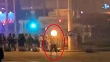 Záznam z pouličních kamer, zachycující smrt demonstranta Alexandra Tarajkovského (označeného červeným kroužkem). Na záznamu se objevuje výrazný záblesk, označovaný odpůrci oficiální verze za výstřel