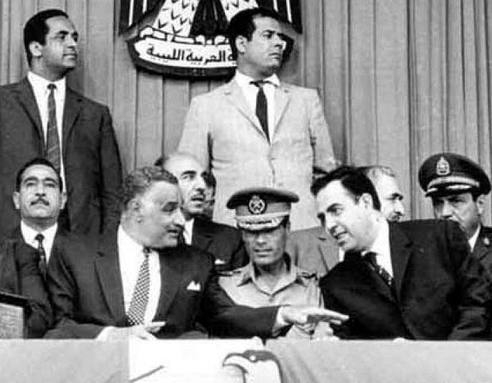 Kaddáfí na arabském summitu v Libyi v roce 1969, krátce po zářijové revoluci, která svrhla krále Idrise. Kaddáfí sedí v uniformě uprostřed s egyptským prezidentem Násirem (vlevo) a syrským presidentem al-Atasím (vpravo)