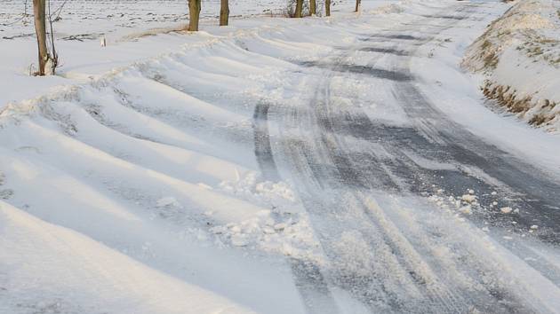 Sněhové jazyky na zaváté silnici - ilustrační foto.