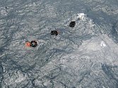 Tři záchranné čluny vznášející se nad potopeným trajektem v otevřených vodách Papuy-Nové Guineje.