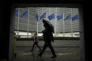 Chodci během deštivého počasí v Bruselu míjejí sídlo Evropské unie na snímku z 16. října 2019
