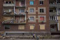 Žena s kočárkem jde kolem domu zničeného ruským bombardováním ve městě Slovjansk v Doněcké oblasti.