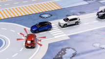 Modré auto se chystá vjet na kruhový objezd - varovat ho klaksonem je na místě.