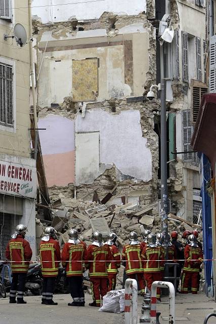 Záchranáři prohledávají trosky zřícených budov v Marseille.