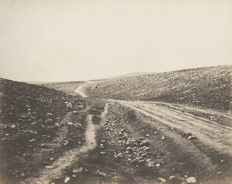 Údolí stínu smrti (Krymská válka, 1855). Pionýr válečné fotografie Roger Fenton. Vznikly dva snímky - cesta plná dělostřeleckých koulí a cesta bez nich