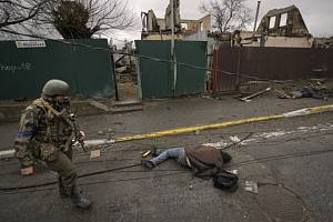 Ukrajinský voják prochází kolem těla civilisty v osvobozené Buči.