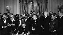 Prezident Lyndon B. Johnson podepisuje 2. července 1964 zákon o občanských právech. Přihlíží Martin Luther King Jr. a další