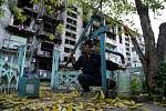 Ukrajinský civilista pumpuje vodu před zničenou obytnou budovou v Ukrajinci osvobozeném Lymanu