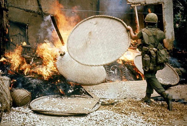 Příslušník 23. divize Americal zapaluje stavení ve vietnamské osadě My Lai po vyvraždění jejích obyvatel.