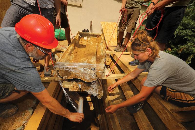 Opatrné vyzvedávání rakve s ostatky Gregora Johanna Mendela z hloubky 2,5 metru. Nejvíce poškozenou část rakve archeologové zabalili do plastové fólie (dole)