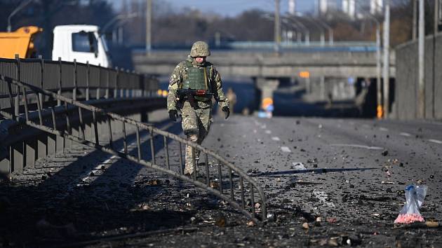 Ukrajinský voják prochází místem zasaženým během bojů o Kyjev. Ilustrační foto.