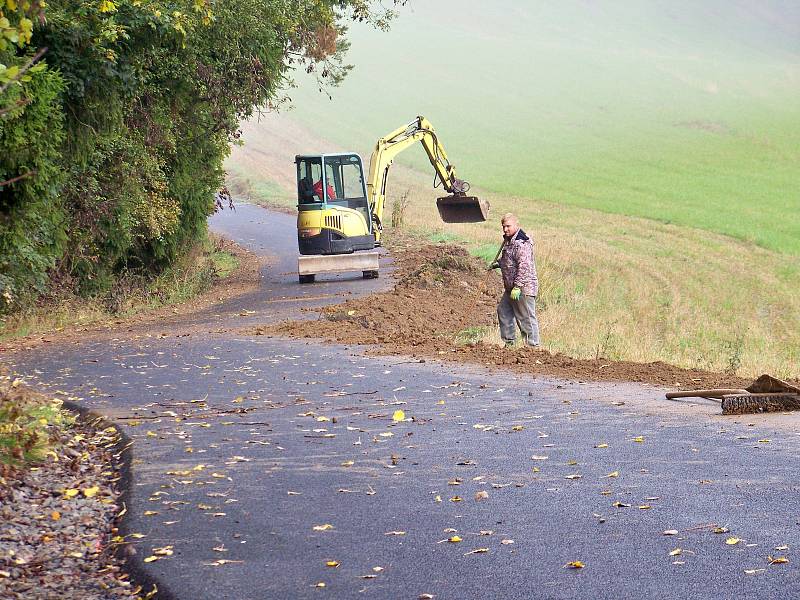 Státní pozemkový úřad zaplatil opravu cest, které z krajské silnice vybočují, a tak z této zničené silnice nyní vedou krásně vyasfaltované cesty k lesu. Právě se tu pracuje...