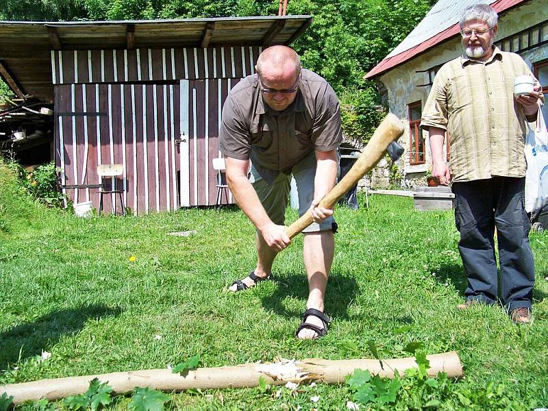 Archeolog Jan Prostředník seká kamenou sekyrkou.Přihlíží Vladimír Šrein.