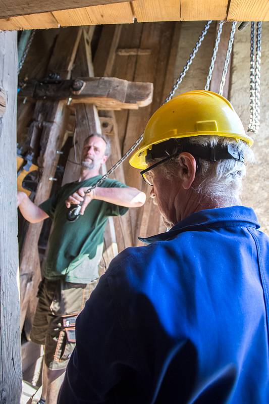 Zvonaře Petr Rudolf Manoušek (se žlutou helmou) dohlíží na instalaci zvonů ve věži kostela svatého Václava v Harrachově.