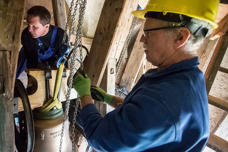 Zvonaře Petr Rudolf Manoušek (se žlutou helmou) dohlíží na instalaci zvonů ve věži kostela svatého Václava v Harrachově.