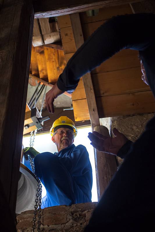 Zvonaře Petr Rudolf Manoušek (se žlutou helmou) dohlíží na instalaci zvonů ve věži kostela svatého Václava v Harrachově.