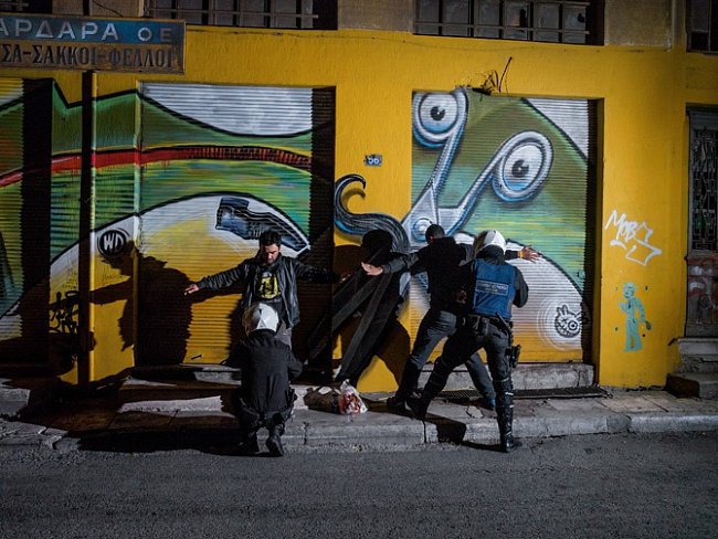 Policisté prohledávají mladého muže na Aischylově ulici nedaleko náměstí Omonia v Athénách. Od začátku krize se v této oblasti častěji vyskytují drogy, prostituce a AIDS. 