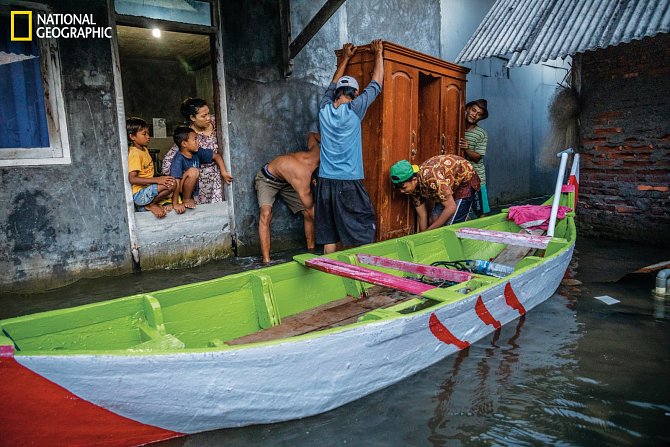 Sousedé pomáhají rodině ve vesnici Timbulsloko naložit nábytek na loď, která ho dopraví do jejich nového domova na sušší zemi.