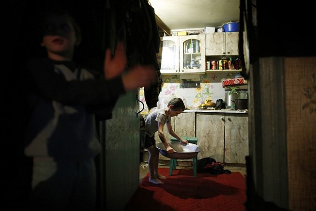 Chlapec si připravuje lavor s teplou vodou, ve kterém se bude koupat. Zorin, Ukrajina