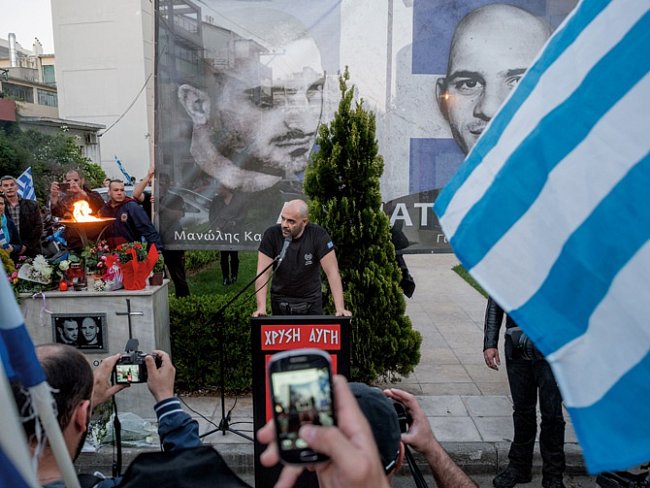 Příslušník Zlatého úsvitu uctívá památku Manolise Kapelonise a Giorgose Fountoulise, kteří byli zastřeleni v listopadu 2013 odplatou za smrt antifašistického rappera Pavlose Fyssase.