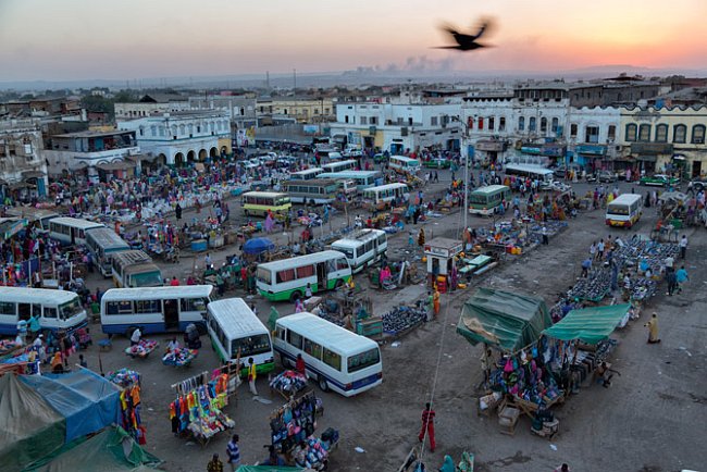 Městská oáza, ústřední trh v Džíbútí, pulzuje životem. Autobusy přivážejí migranty, kteří se, jak říká Salopek, během jedné generace proměnili v tomto půlmilionovém městě z tradičních pastevců v pilně
